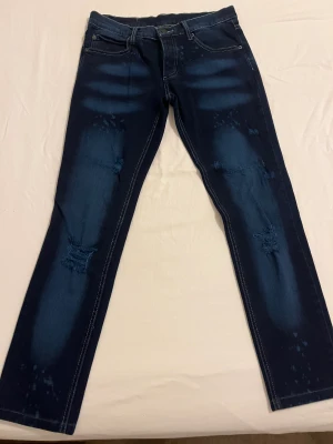 Låg midja Jeans  - Mörk blåa jeans med små ljusa delar på jeansen. De är köpta i London 2006. Storlek på jeansen är 26.