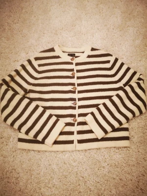 Massimo Dutti cardigan - Massimo Dutti randig cardigan med gula knappar.  Cremefärgad /khaki. Den är jättebra kvalitet 100 % tjock bomull. Använt bara 1 gång. Den är superfin och jättebra i skick. Säjlre darför den här cardigan är för stor för mig.  Köpte för 999 kr.  Storlek L. 