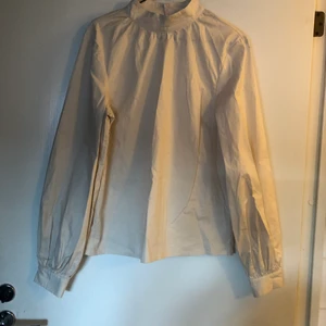 Cremevit blus Na-kd 36 puffärmar - Blus med hög krage från na-kd. Elegant och perfekt till våren. Bara använd en gång- nyskick. 