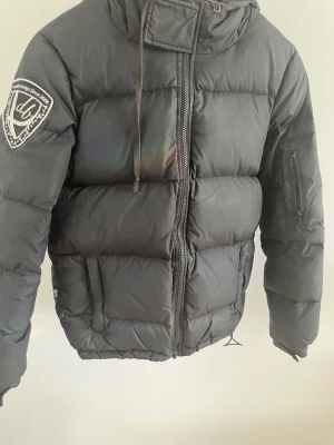 Svart dunjacka  - En svart dunjacka med luva från Dbrand i storlek XS, har använts några enstaka gånger! 
