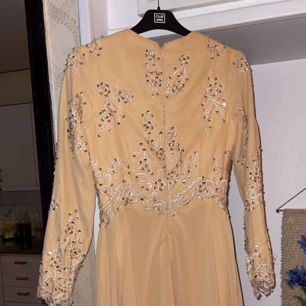 En beige maxiklänning med långa ärmar, använt 1 gång, nyskick. Paljetter på framsidan och baksidan av klänningen. Köpt från London. . Klänningar.