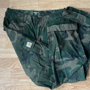 Carhart Wip - Säljer ett par camoflage Carhart byxor som endast är använda 2ggr. storlek 31/34 och väldigt bra skick!!🙌🏼 stora fickor bak, fram och på sidan med knäppning. Nere vid foten kan man dra åt och knyta. 💚🤎