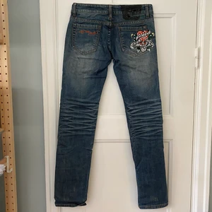 Ed Hardy jeans - Säljes dessa low waist och raka Ed Hardy jeansen. Bra skick förutom att baklappen är lite trasig. Storlek 27. Midjan är 80 cm och längden för innerben är 81 cm.