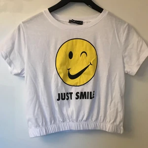 New Yorker FB Sister T-shirt med tryck - Denna vita tröja med ett smiley tryck och texten ”JUST SMILE” är använd en gång och är köpt från New Yorker. Tröjan har resår längst ner och är i storlek M. Hör gärna av dig om du skulle undra något! <33