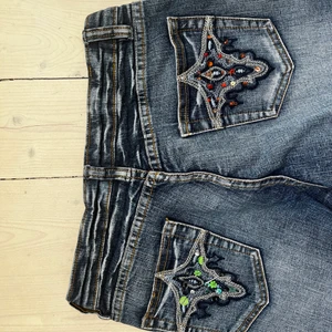 Jeans med broderier  - Sjukt snygga jeans med broderier på bakfickorna!! Skulle säga att dem är låg/mid waste och sitter rakt i benen! Angiven storlek i byxorna är 36 (alltså small i vanlig storlek) i byxstorlek skulle jag tippa på 27,32🥰 Måtten är: innerbenslängd 75 cm, midjemått 38. 💕 Hör av dig för fler bilder! Köp direkt för 500kr