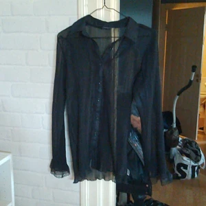 Svart genomskinlig skjorta  - Svart genomskinlig skjorta med lite spets i nyskick men avtagen lapp