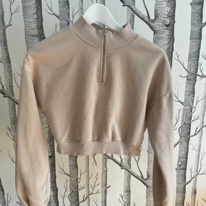 Croppad sweatshirt från Nelly - Beige croppad sweatshirt med halv dragkedja från Nelly. Storlek S. Polo-krage.