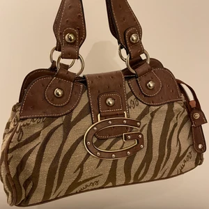 Guess Väska - väldigt y2k guess väska. inte äkta!! köpt på secondhand och använd en gång. lite missfärgning på insidan men annars är väskan i väldigt bra skick! skriv för mer bilder. frakt tillkommer