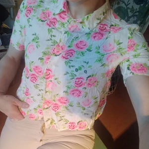 Skjorta med rosor - Vit, ganska kort, skjorta med rosor i en färg som nästan är åt det neonrosa hållet, syns inte riktigt på bilderna dock. Men både färgmässigt och modellmässigt är det en snygg skjorta som är lite annorlunda = har lite personlighet! Kommer från H&M.