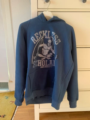 Reckless Scholars hoodie - Tung och skön rhinestone hoodie av märket Reckless Scholars, inga ”stenar” saknas, använd ett fåtal gånger. Säljes på grund av att jag inte använder den längre. Sitter som en M.