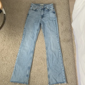 Ljusblå bootcut jeans - Säljer dessa ljusblå mid waist jeans från Gina Tricot för att de är för små. Sparsamt använda, max 5 ggr ungefär. Står inte för postarens slarv. Storlek 32. Nypris 599 kr, säljer direkt för 350  kr + frakt.