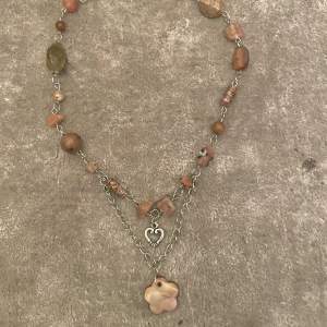 Egentillverkat halsband i orange/bruna pärlor med charms.
