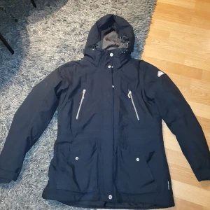 Täckjacka - Svart täckjacka i figurnära modell från Everest. Är använd men i bra skick.