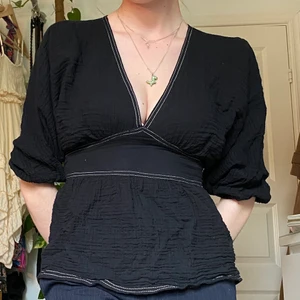 Svart blus från ASOS stl S/M - Svart blus med vita sömmar, puffiga ärmar, låg v-ringning och snävare midja från ASOS. Etiketten säger stl 34 men är stor i storleken så skulle säga S/M i stl.   Du som köper står för frakt, möts annars upp vid Stockholm city.