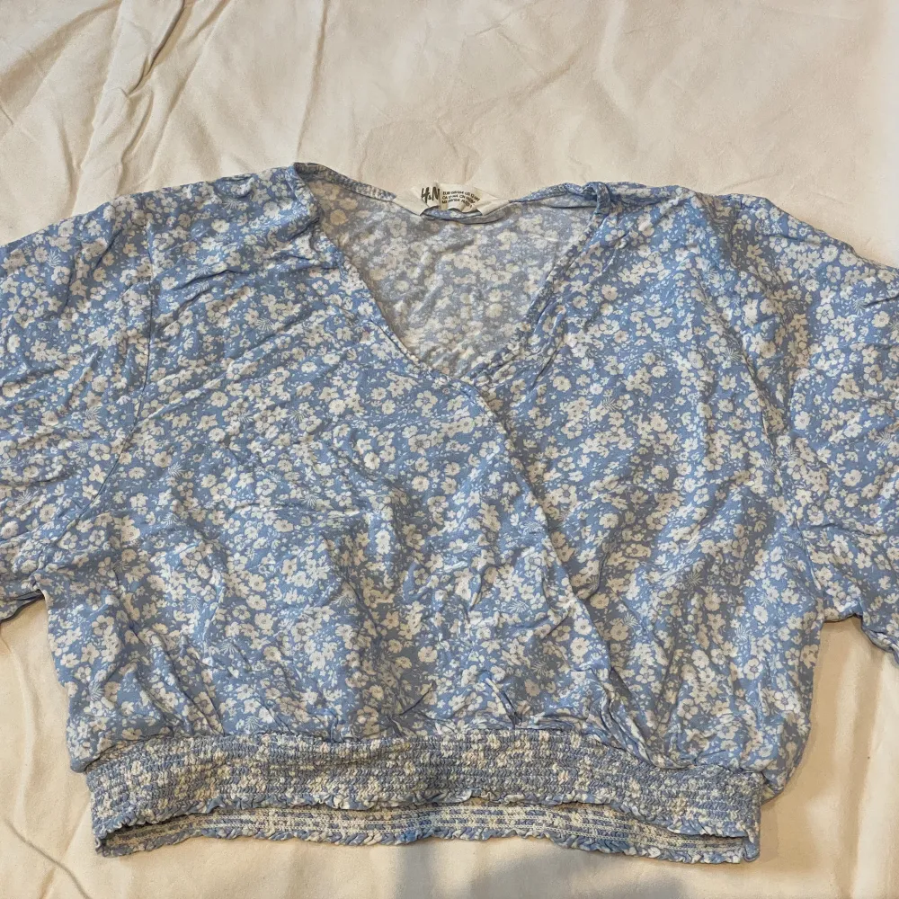 En jätte fin gullig sommartopp från H&M. Den är babyblå med fina vita små blommor. Perfekt för sommaren eftersom den är tunn och kort. Jag har tyvärr inte använt denna och det är inga defekter, den e nästan som ny. . Blusar.