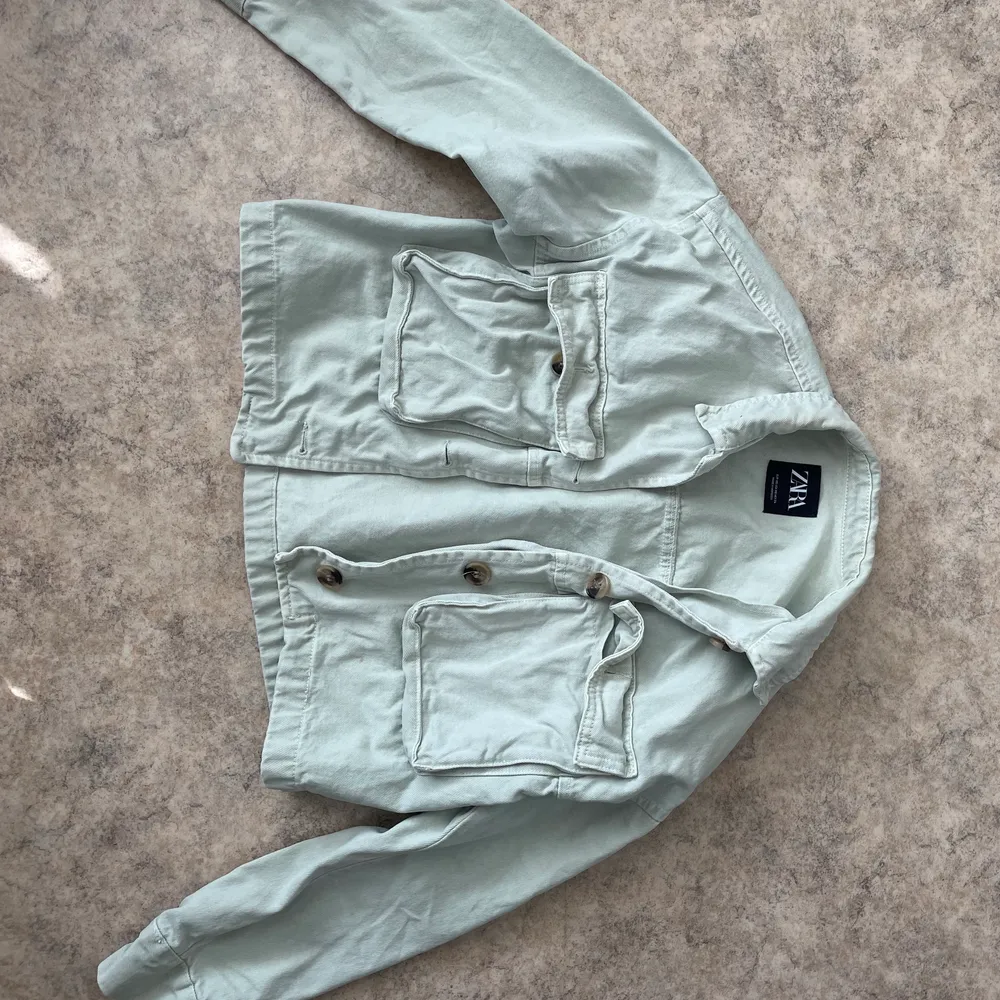 Mintgröna croppad jeansjacka från Zara i storlek XS, en knapp saknas vid höger ficka. . Jackor.