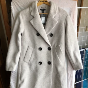 Newlook coat beige/grå - Helt ny. Är 154 cm och tyvärr var den lite för stor och lång på mig, är du 158 och lite längre funkar det bra. Den är rätt så tjock, tillräckligt varm för en riktig kall höstväder, dock osäker under vintern. Skicka meddelande för mer detaljer.