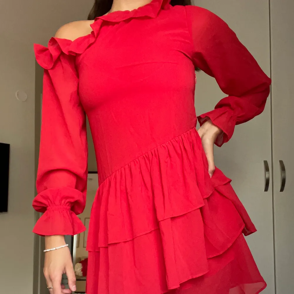 Otrooolig klänning med vackra volanger i den mest perfekta röda färgen! Klänningen är i ett tunt och svalt material och har en cut out över vänster axel (se bild). Köparen står för frakt 💃🏽💃🏽💃🏽. Klänningar.