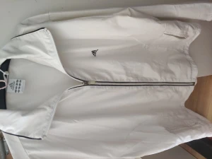 Adidas vindjacka vit - Väldigt tunt material och har använts väldigt ofta. Det finns några fläckar på insidan av jackan och vid änden av armen. 