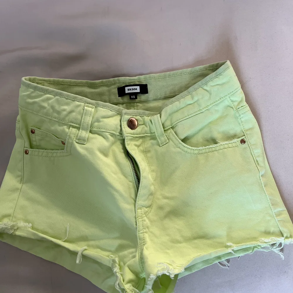 Ett par limegröna jeansshorts från BikBok, koppar färg på knappen och detaljerna vid fickorna, lite fransar vid benen, normalhög/ hög midja skulle jag nog säga.. Shorts.