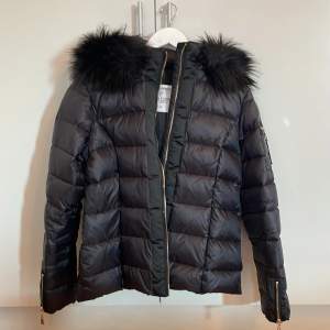 Bubbleroom/Chiara Forthi Madesimo Down Jacket Black. Knappt använd dunjacka med huva och fuskpälskrage. Säljes på grund av att den är lite för liten i storleken. Det är snarare 42 än 44. Jackan är i nyskick 