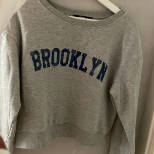 Grå sweatshirt  - En grå croppad sweatshirt med blå text på. Skulle även passa som en small. Skriv för fler bilder 