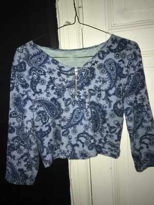 Blå magtröja - Blå magtröja med bohemiskt mönster. Dragkedja vid brösten. 3kvarts ärmar. 