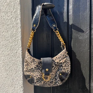 Handväska  - Supercool väska i (fake) skinn/pälsmaterial som är köpt i Barcelona. 25 cm lång och 14 cm hög (mätt från mitten). Lite sliten på bandet, syns på bild 2. Därav kan pris diskuteras!