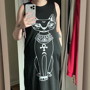 Svart klänning med motiv - Det här är en svart klänning med motiv som jag säljer pga jag aldrig använt den. Den går ner till lite under knäna.