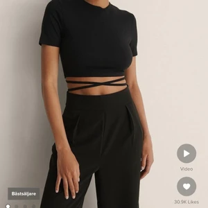 Topp med band  - Säljer denna snygga svarta topp i stl S som har en croppad längd och en öppen rygg med en omlottstil. Köpt från NA-KD för 249 kr. Frakten ingår ej i priset. 