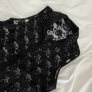 Kortärmad blus/skjorta i svart spets, med krage och svarta diamantdetaljer