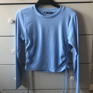 Blå topp med snygg resor på sidan - Blå långärmad tröja med resor på sidan. Använt ett fåtal gånger och är i fint skick