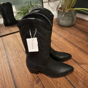 Cowboyboots - Säljer ett par helt oanvända svarta cowboyboots från Stradivarius. Lappen sitter kvar! Storleken på lappen är 39 men skulle absolut säga att det är en 38, då jag säljer eftersom dem är för små!