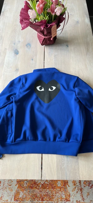 CDG Track Jacket - CDG Play Track jacka köpt begagnad men i mycket bra skick! Vestiaire Collective verified. Digitalt kvitto finns. Storlek M. Sitter bra på mig som är 177 lång.