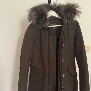 Woolrich parka - Mörkbrun vinterjacka från Woolrich i storlek XS, dam. Passar S-M.  Jättefint skick. Använd sparsamt. 