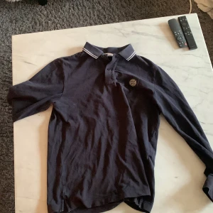 Stone island långärmad piké  - Säljer nu denna extremt snygga Stone island piké för endast 500 kr den säljes för att den är lite för liten för mig. Storleken är S men passar nog en M. Skick 9/10 inga defekter. Köptes på Nk i sommras.