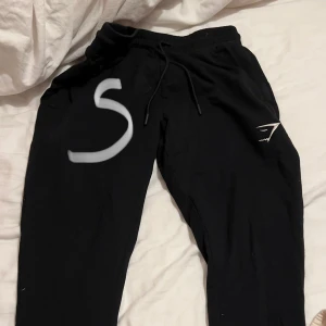 Svarta mjukisbyxor från Gymshark - Säljer ett par svarta mjukisbyxor från Gymshark i storlek S. De är superbekväma med en elastisk midja och snörning för perfekt passform. Perfekta för både träning och mysiga dagar hemma. 🖤