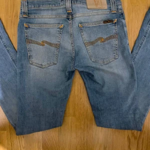 Nuddie jeans  - Hej säljer dessa ljusblåa Nuddie jeans som är i storlek W26 och L32. ⚜️💯 Jeansen är i bra skick men lappen där bak är lite utsuddad men är inte något som syns! Kom gärna med prisförslag! Jag kan gå ner i pris vid snabb affär. 📦🔥💯
