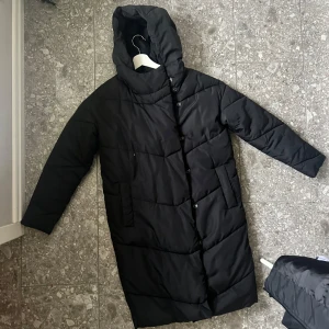 Noisy may dunjacka - Lång dunjacka med knappar.  Hög i kragen vilket gör den väldigt varm med en luva. 500kr inkl spårbart frakt. XS