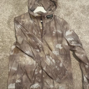 windbreaker från Woolrich - Säljer en vindjacka från Woolrich. Jackan har en dragkedja framtill och en praktisk huva. Perfekt för blåsiga dagar och ger en avslappnad stil.