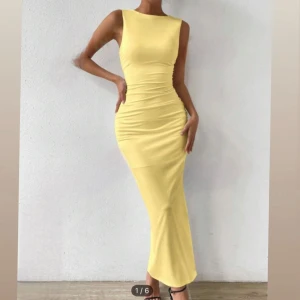 Gul långklänning - Elegant gul långklänning med tight passform och slits. Klänningen är ärmlös och har en stilren design som framhäver figuren.