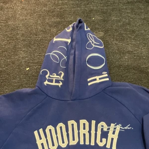 Blå hoodie från Hoodrich - Snygg blå hoodie från Hoodrich med tryck på både huva och ärmar. Den har en stor ficka framtill och texten 'FROM NOTHING TO SOMETHING ' vid fickan. Perfekt för en avslappnad stil.