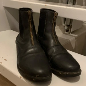 Svarta ridskor med fungerande dragkedja  - Ridskor i storlek 38! De e i nyskick och dragkedja på båda skor är som de ska. Kan tvättas upp innan de skickas! Nypris 600kr jag säljer för 300 (kan prutas ner)  (Tryck inte på köp nu! )