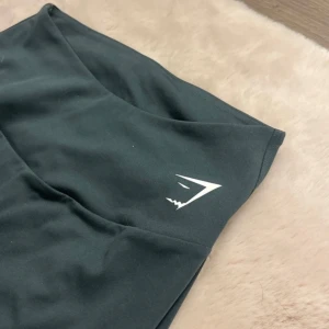 Svarta leggings från Gymshark - Snygga mörk gröna leggings från Gymshark med hög midja. Perfekta för träning eller en aktiv vardag. De är tillverkade i ett stretchigt material som ger en tight passform och bra rörelsefrihet. Alldrig använda! 