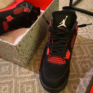 Nike Air Jordan 4 Retro - Snygga Nike Air Jordan 4 Retro i svart och röd färg. Skorna har en ikonisk design med snörning och Jumpman-logga. Perfekta för sneakerheads som vill ha en klassisk stil.