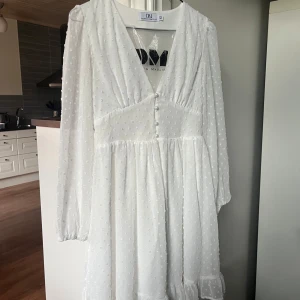 Vit klänning från Dennis Maglic - Superfin vit klänning från Dennis Maglic. Klänningen har långa ärmar och knappar framtill. Tidigare använd endast 1 gång, säljer då den var för liten för mig ☺️