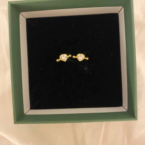 Guldörhängen med hjärtformad sten - Snygga guldörhängen med en hjärtformad klar sten i mitten. Perfekta för att ge en elegant touch till din stil. Kommer i en fin presentask💞 Endast testade.  Sterling silver 925