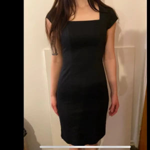 Svart klänning med fyrkantig urringning - Elegant svart klänning med en fyrkantig urringning och korta ärmar. Sparsamt använd, från H&M storlek 34.