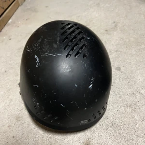 Svart hjälm från Phase - Säljer en svart hjälm från Phase med ventilationshål och justerbart spänne. Perfekt för vintersport och andra aktiviteter. Hjälmen har en robust design och är bekväm att bära.