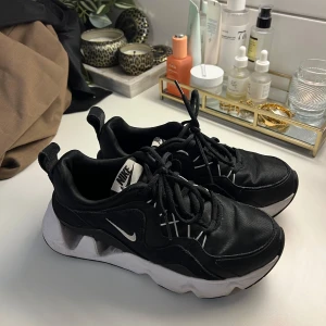 Svarta Nike sneakers - Säljer ett par svarta Nike sneakers med vit sula och snörning. Skorna har en sportig design med Nike-logga på sidan och tungan. Perfekta för en casual look.